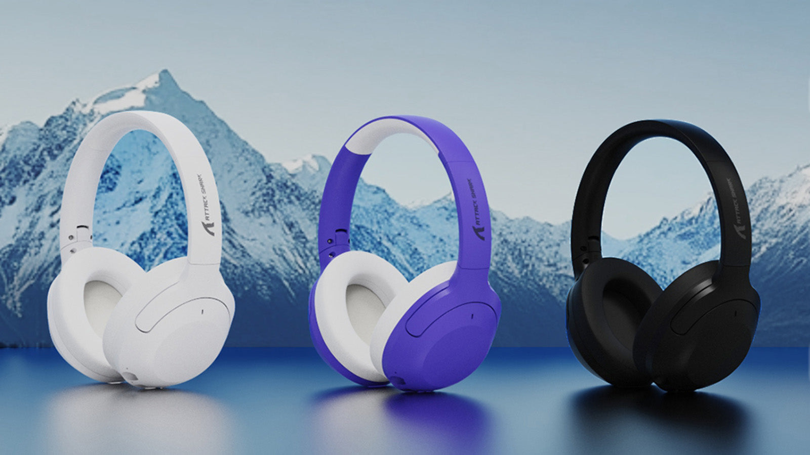 Three Attack Shark wireless headphones in white, purple, and black colors displayed against a mountain landscape background