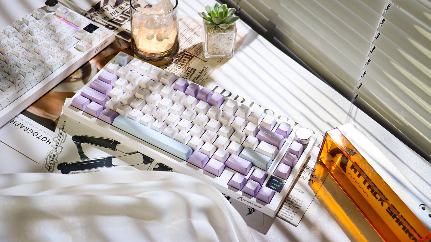 A white 75% mechanical keyboard with white and purple keycaps on a newspaper or magazine