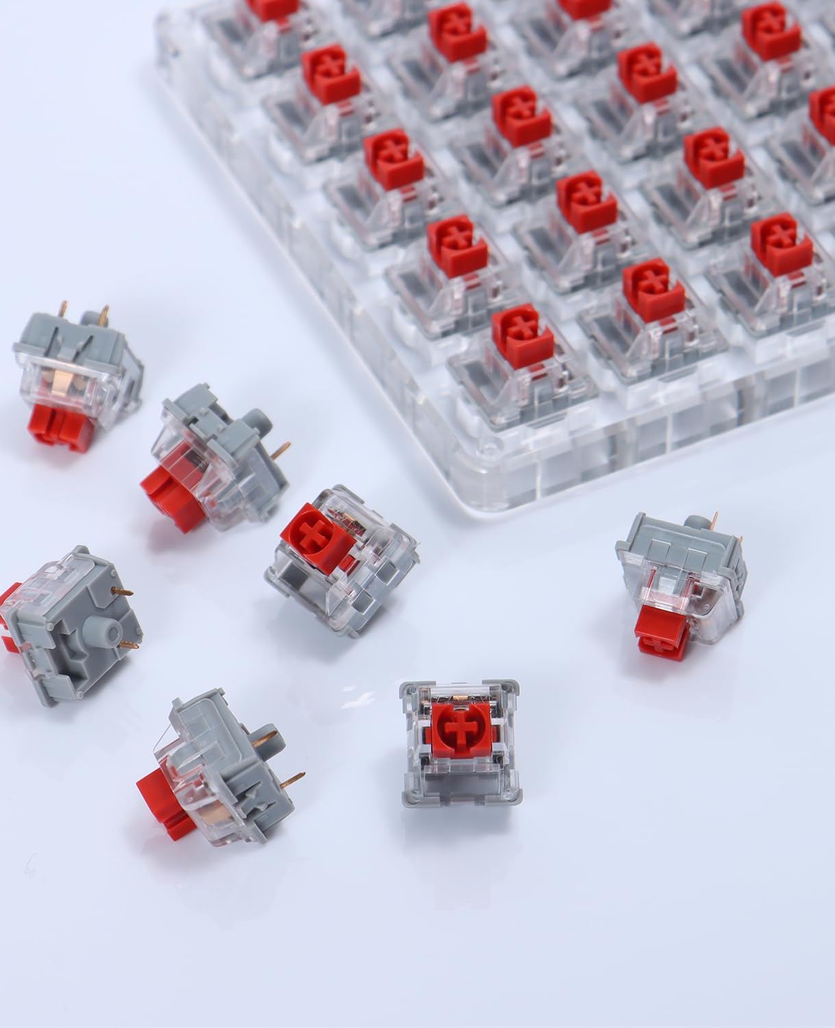 ATTACK SHARK x AJAZZ AS switches with red stems and clear housings, arranged on a clear acrylic tester.